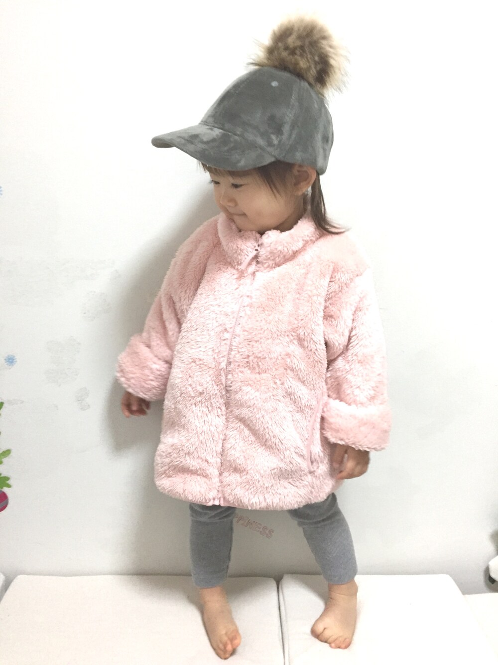 ピンク系のダッフルコート、グレー系のパンツ、グレー系のキャップを着用したキッズの冬コーディネートの1枚目の写真