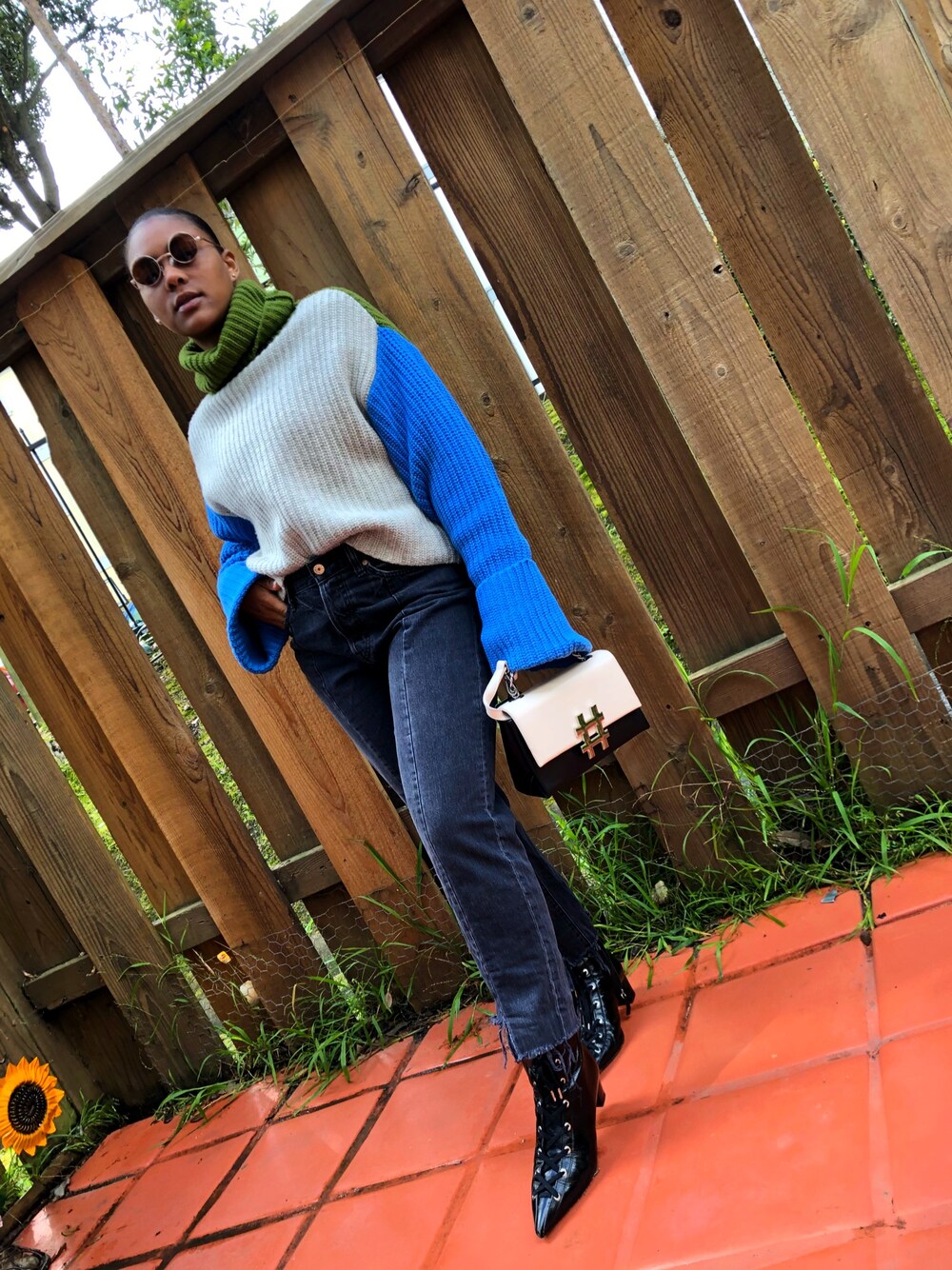 ブラック系のブーツ、ベージュ系のハンドバッグ、ブルー系のニット/セーターを着用したレディースの春コーディネートの1枚目の写真