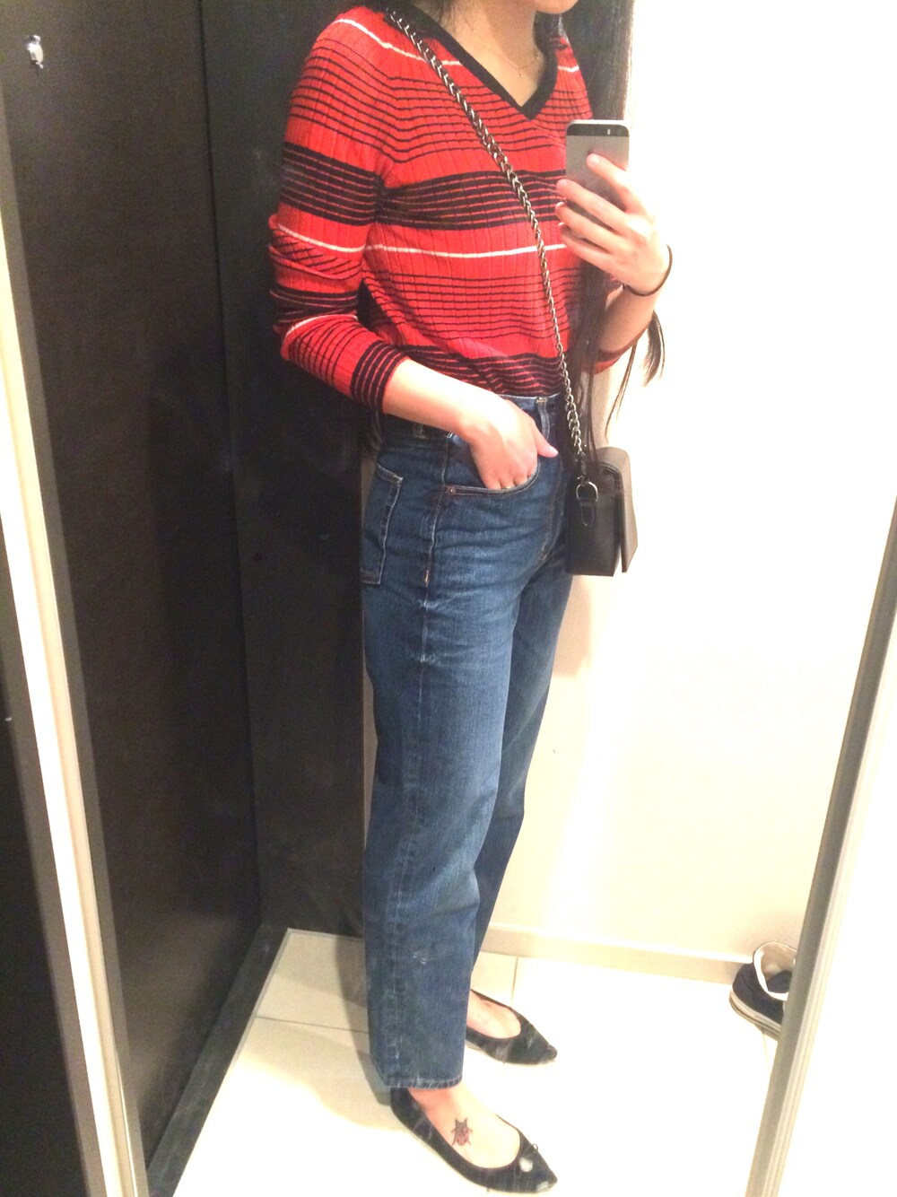 レッド系のニット/セーター、ブルー系のデニムパンツ、ブラック系のバレエシューズを着用したレディースの春コーディネートの1枚目の写真