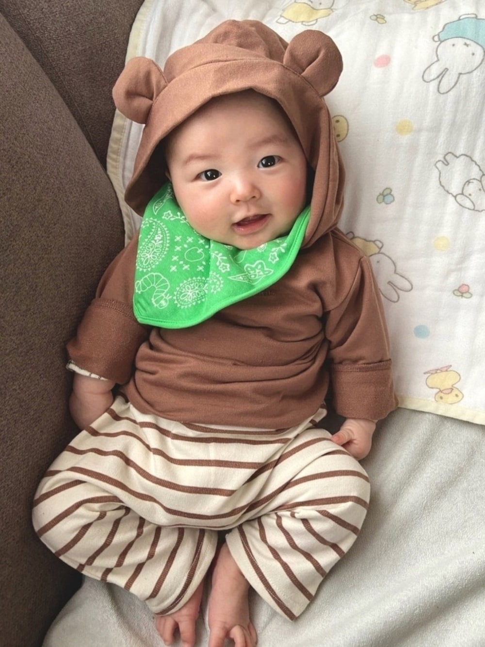 ブラウン系のロンパース、その他のレギンス/スパッツ、グリーン系のスタイ/よだれかけを着用したキッズの冬コーディネートの1枚目の写真