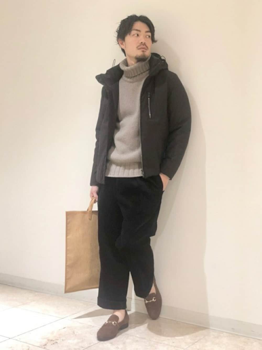 ブラウン系のダウンジャケット/コート、ブラウン系のニット/セーター、ブラック系のその他パンツを着用したメンズの冬コーディネートの1枚目の写真