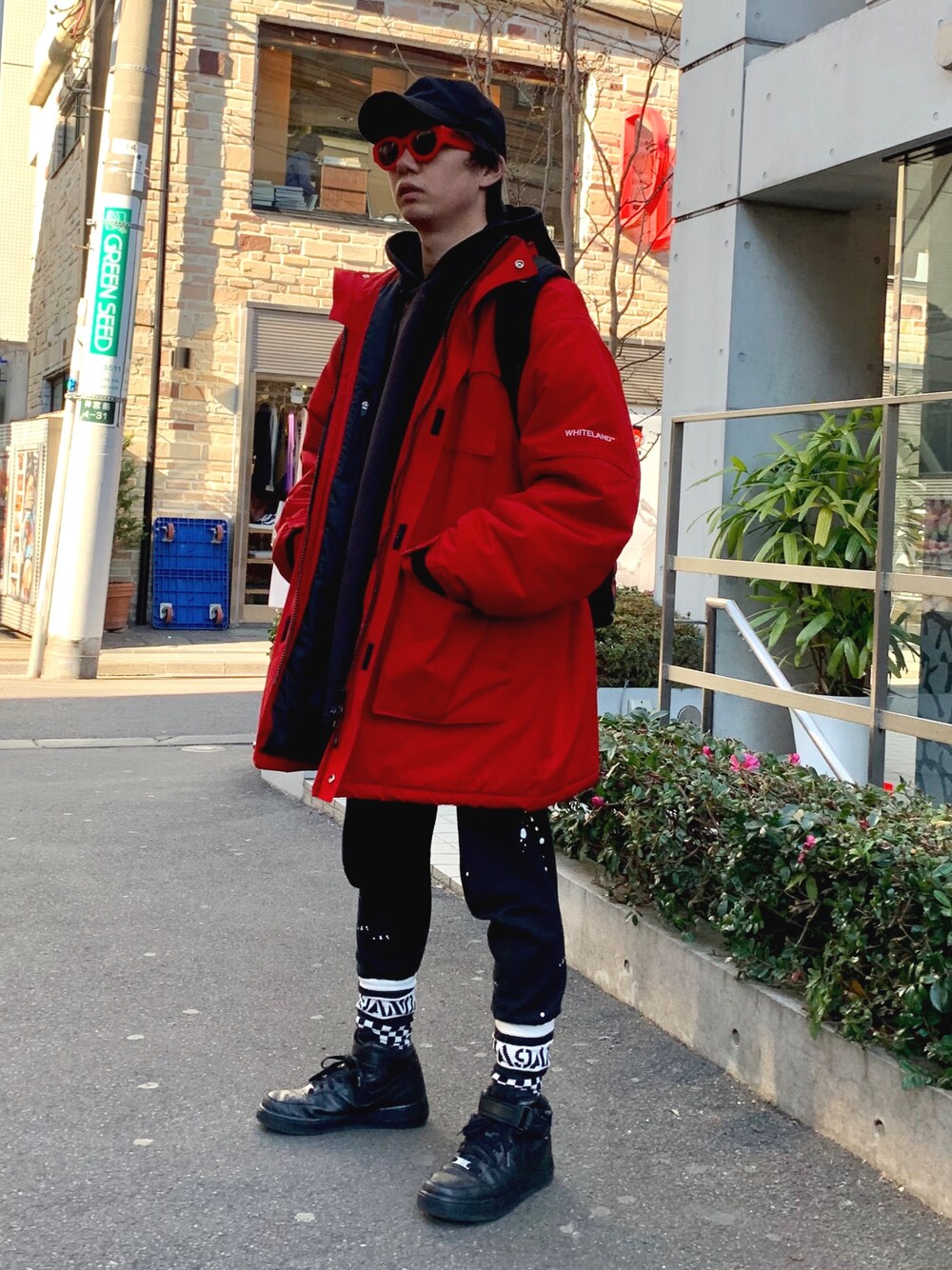 レッド系のミリタリージャケット、ブラック系のスニーカー、レッド系のメガネを着用したメンズの冬コーディネートの1枚目の写真