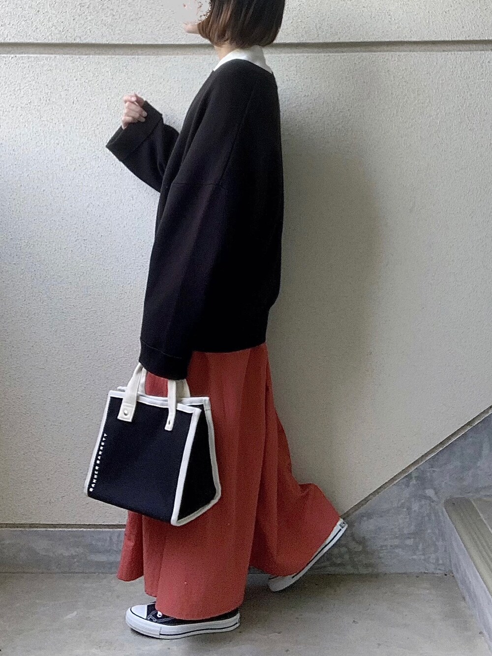 オレンジ系のスカート、ホワイト系のシャツ/ブラウス、ブラック系のカーディガン/ボレロを着用したレディースの春コーディネートの1枚目の写真
