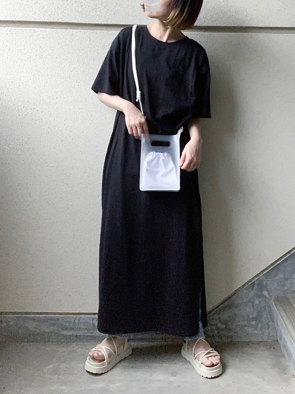 ブラック系のワンピース、ホワイト系のショルダーバッグ、ホワイト系のサンダルを着用したレディースの春コーディネートの1枚目の写真