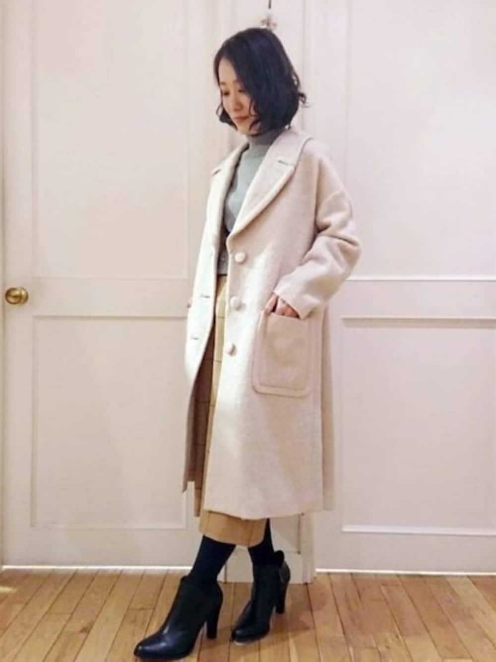 ピンク系のチェスターコート、イエロー系のスカートを着用したレディースの秋コーディネートの1枚目の写真