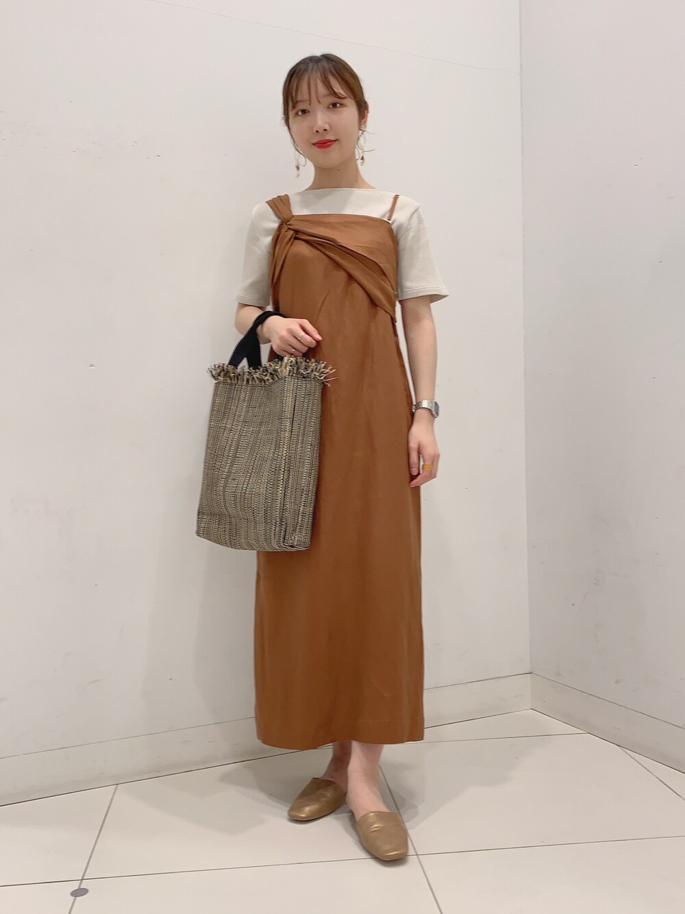 イエロー系のワンピース、ブラック系のトートバッグ、ゴールド系のスリッポンを着用したレディースの夏コーディネートの1枚目の写真