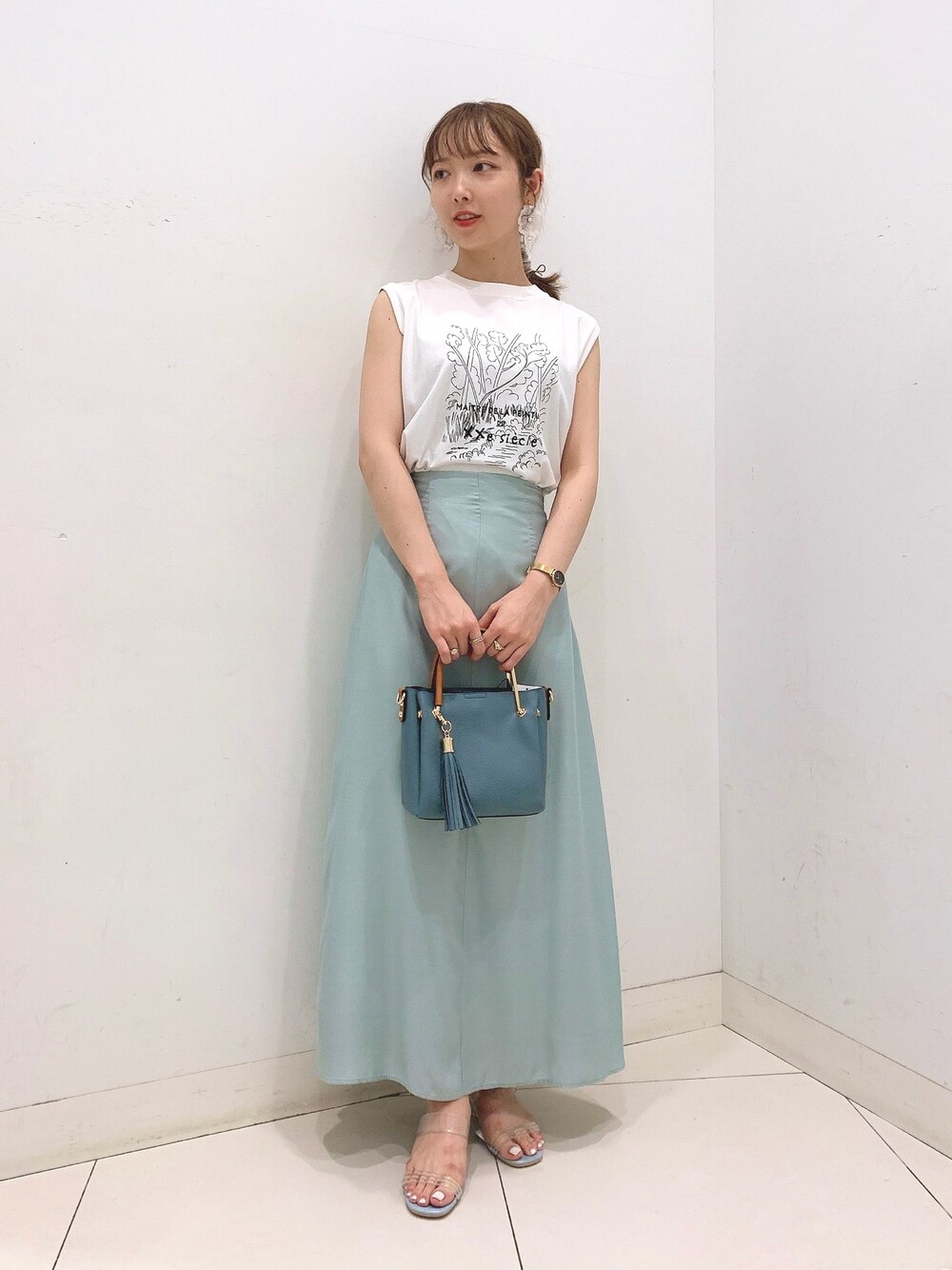 ホワイト系のTシャツ/カットソー、ブルー系のトートバッグ、グリーン系のスカートを着用したレディースの夏コーディネートの1枚目の写真