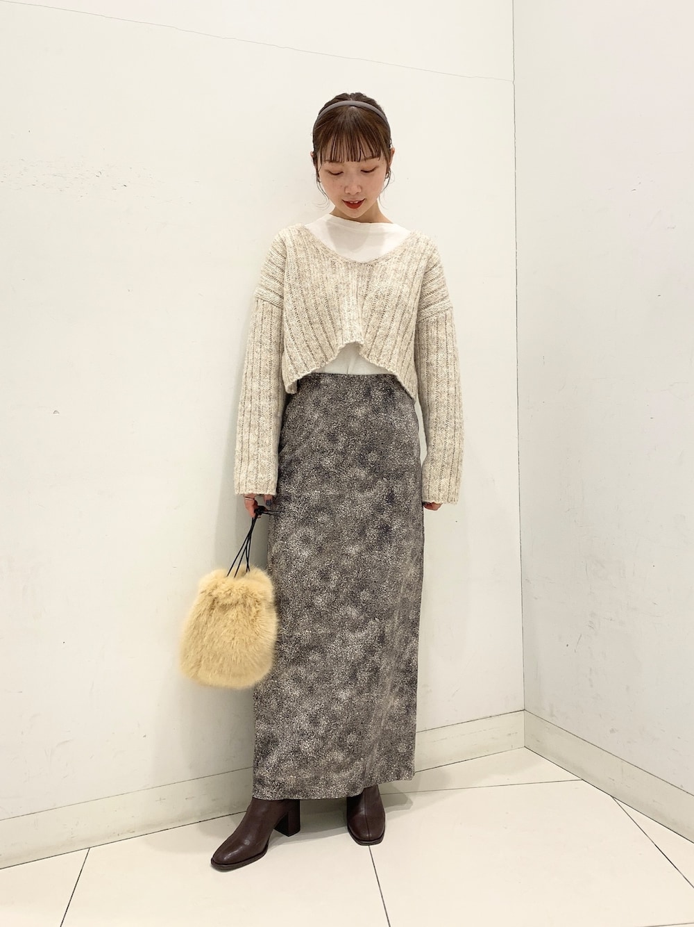 ベージュ系のニット/セーター、ブラック系のスカート、ベージュ系のショルダーバッグを着用したレディースの秋コーディネートの1枚目の写真