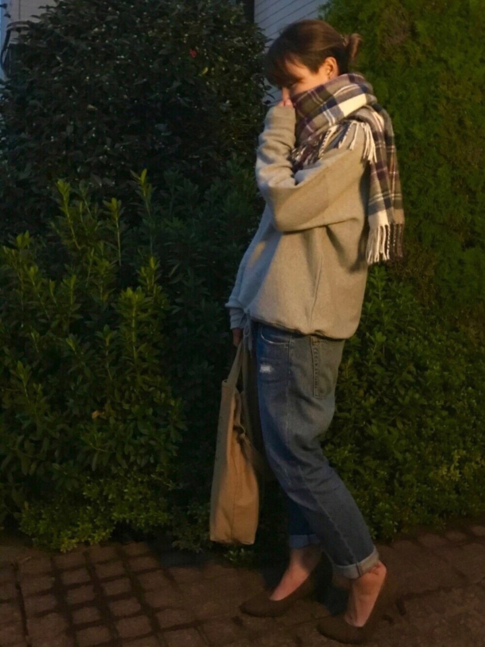 グレー系のスウェット、ブルー系のデニムパンツ、ベージュ系のトートバッグを着用したレディースの秋コーディネートの1枚目の写真