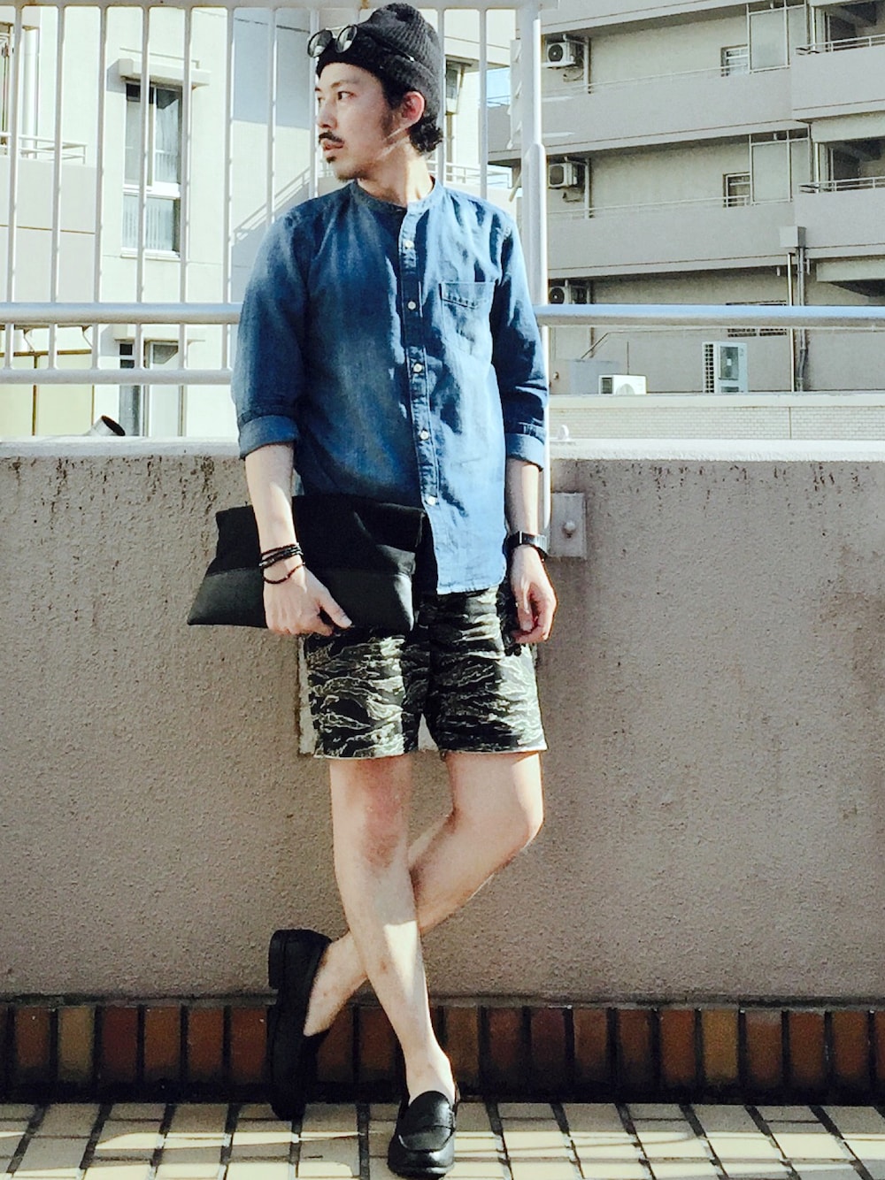 ブルー系のシャツ/ブラウス、ブラック系のクラッチバッグ、グリーン系のパンツを着用したメンズの春コーディネートの1枚目の写真