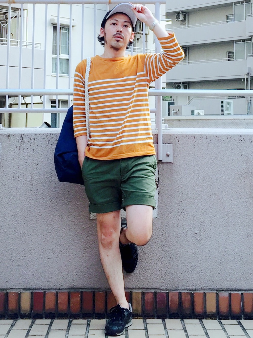 イエロー系のトップス、ブルー系のバックパック/リュック、グリーン系のその他パンツを着用したメンズの春コーディネートの1枚目の写真