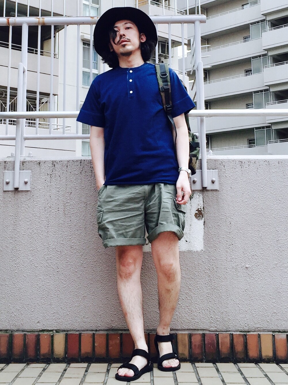 グリーン系のバックパック/リュック、ブルー系のTシャツ/カットソー、グリーン系のカーゴパンツを着用したメンズの夏コーディネートの1枚目の写真