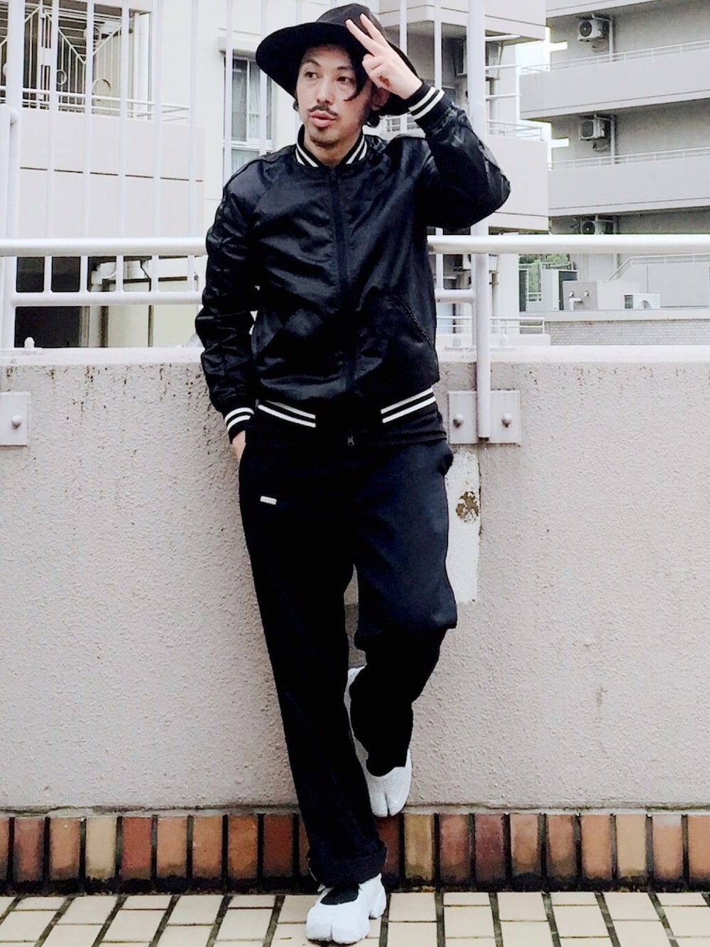 ブラック系のブルゾン、ホワイト系のスニーカー、ブラック系のチノパンツを着用したメンズの秋コーディネートの1枚目の写真