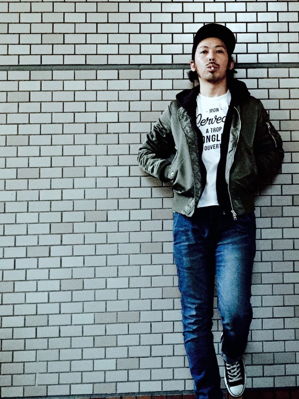 グリーン系のMA-1、ブルー系のデニムパンツ、ブラック系のスニーカーを着用したメンズの秋コーディネートの1枚目の写真