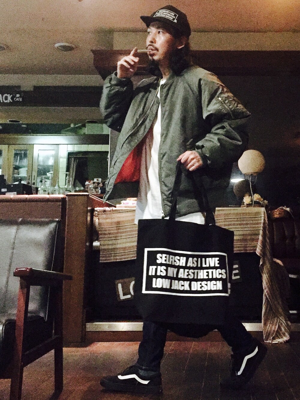 ブラック系のトートバッグ、ブラック系のスニーカー、グリーン系のMA-1を着用したメンズの秋コーディネートの1枚目の写真