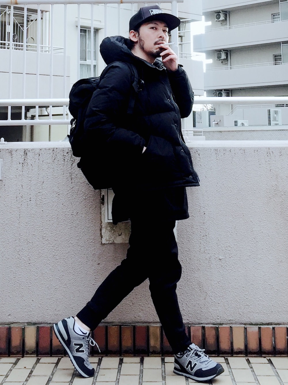 ブラック系のダウンジャケット/コート、ブラック系のTシャツ/カットソー、ブラック系のバックパック/リュックを着用したメンズの冬コーディネートの1枚目の写真