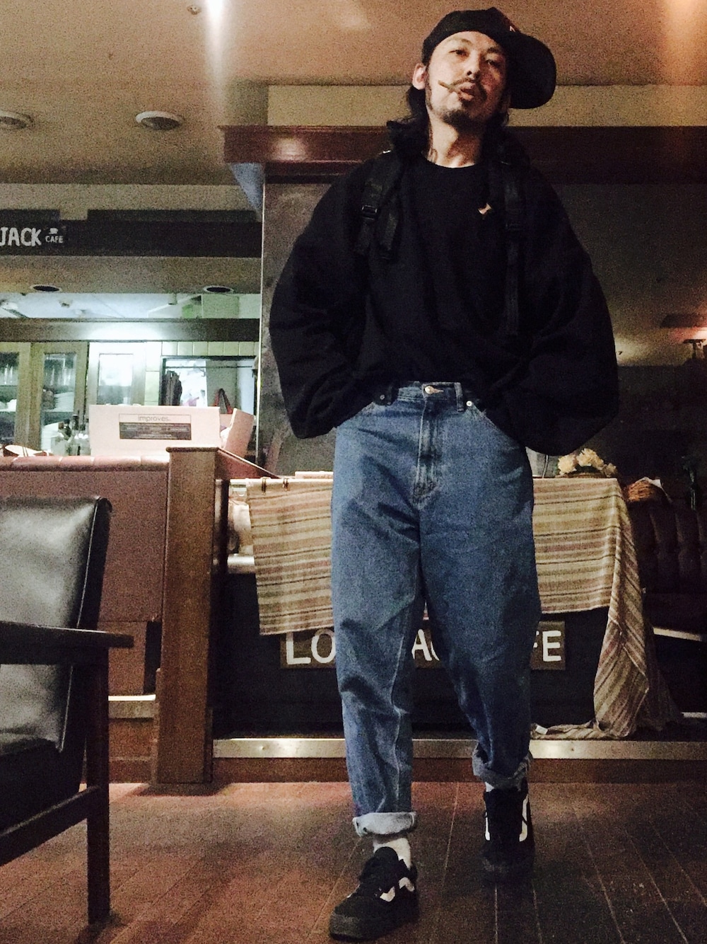 ブラック系のバックパック/リュック、ブラック系のスウェット、ブルー系のデニムパンツを着用したメンズの冬コーディネートの1枚目の写真