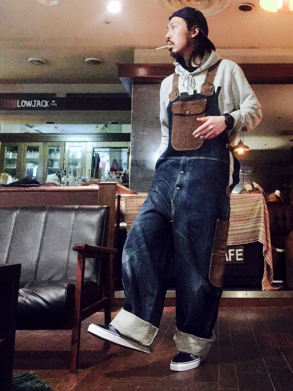 ブルー系のスニーカー、ブルー系のサロペット/オーバーオール、パープル系のキャップを着用したメンズの春コーディネートの1枚目の写真