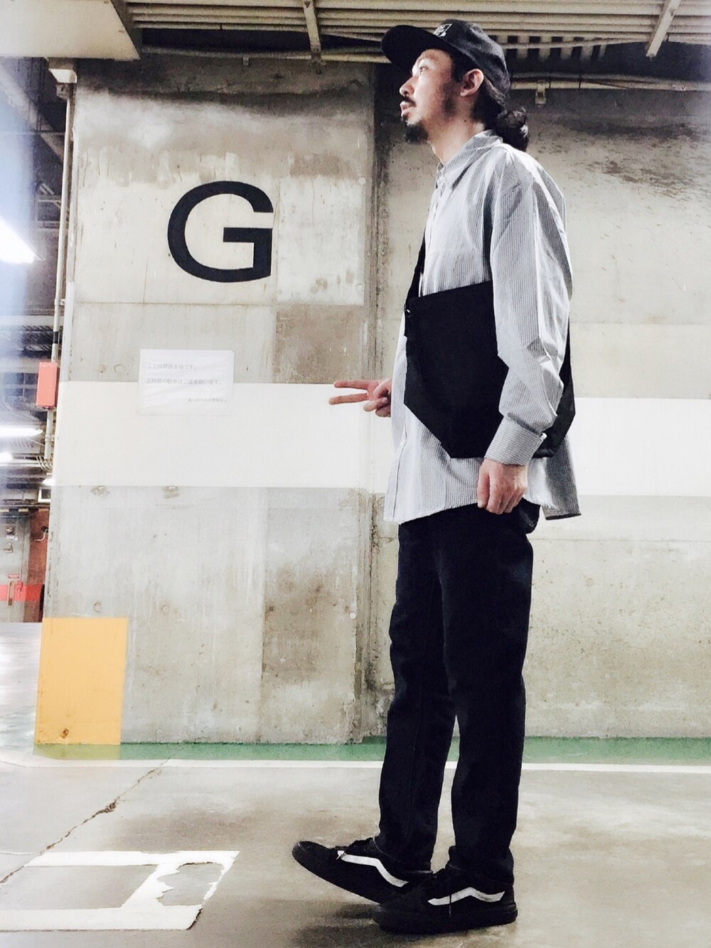 ブラック系のショルダーバッグ、ブラック系のスニーカー、ブルー系のデニムパンツを着用したメンズの秋コーディネートの1枚目の写真