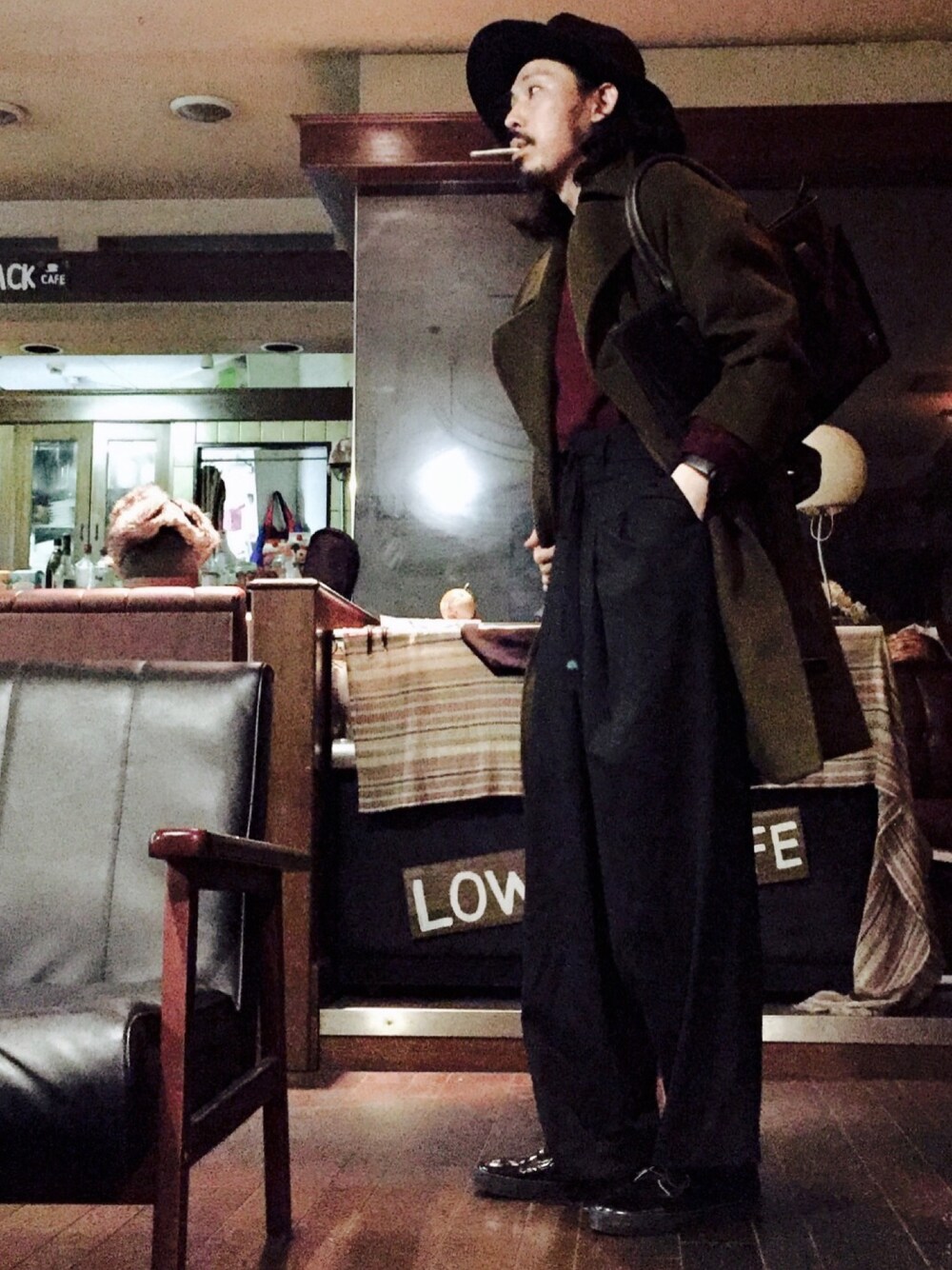 グリーン系のチェスターコート、レッド系のニット/セーター、ブラック系のその他パンツを着用したメンズの秋コーディネートの1枚目の写真