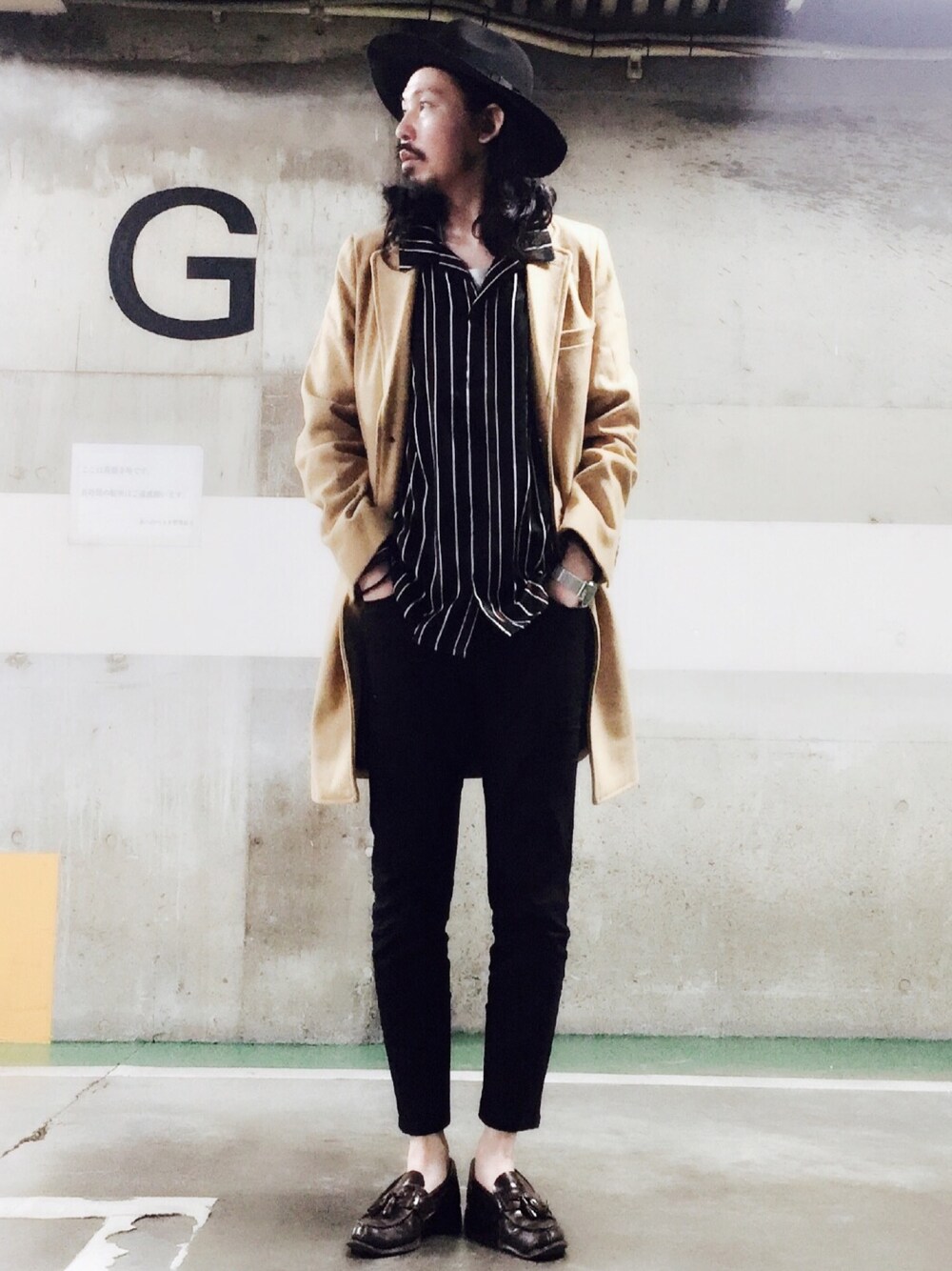 ベージュ系のチェスターコート、ブラック系のシャツ/ブラウス、ブラック系のチノパンツを着用したメンズの秋コーディネートの1枚目の写真