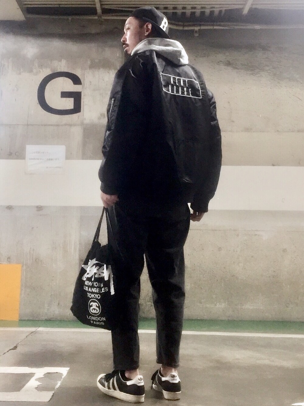 グレー系のパーカー、ブラック系のデニムパンツ、ブラック系のスニーカーを着用したメンズの冬コーディネートの1枚目の写真