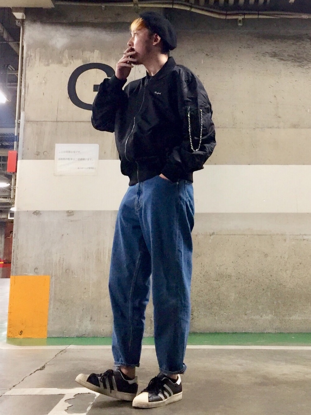 ブルー系のデニムパンツ、ブラック系のスニーカー、ブラック系のMA-1を着用したメンズの冬コーディネートの1枚目の写真