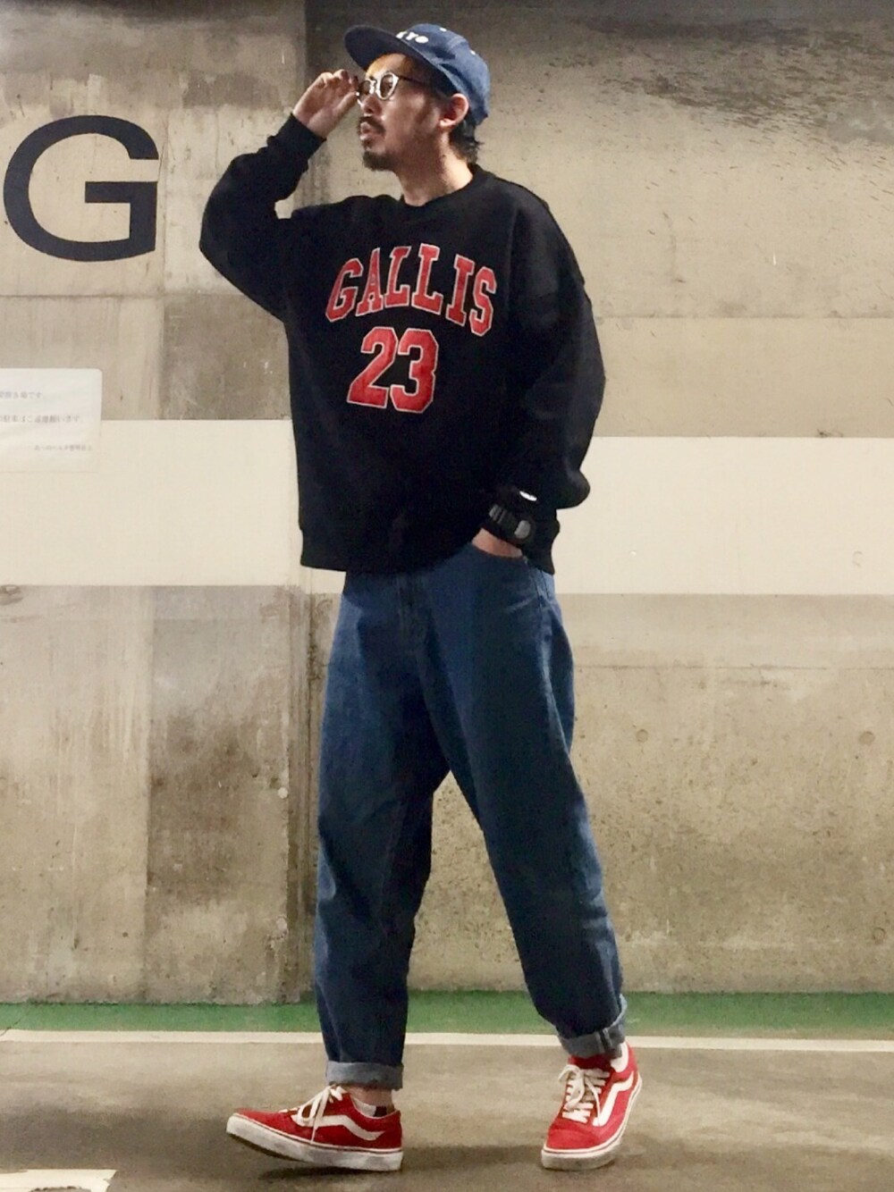 ブラック系のスウェット、ブルー系のデニムパンツ、レッド系のスニーカーを着用したメンズの春コーディネートの1枚目の写真