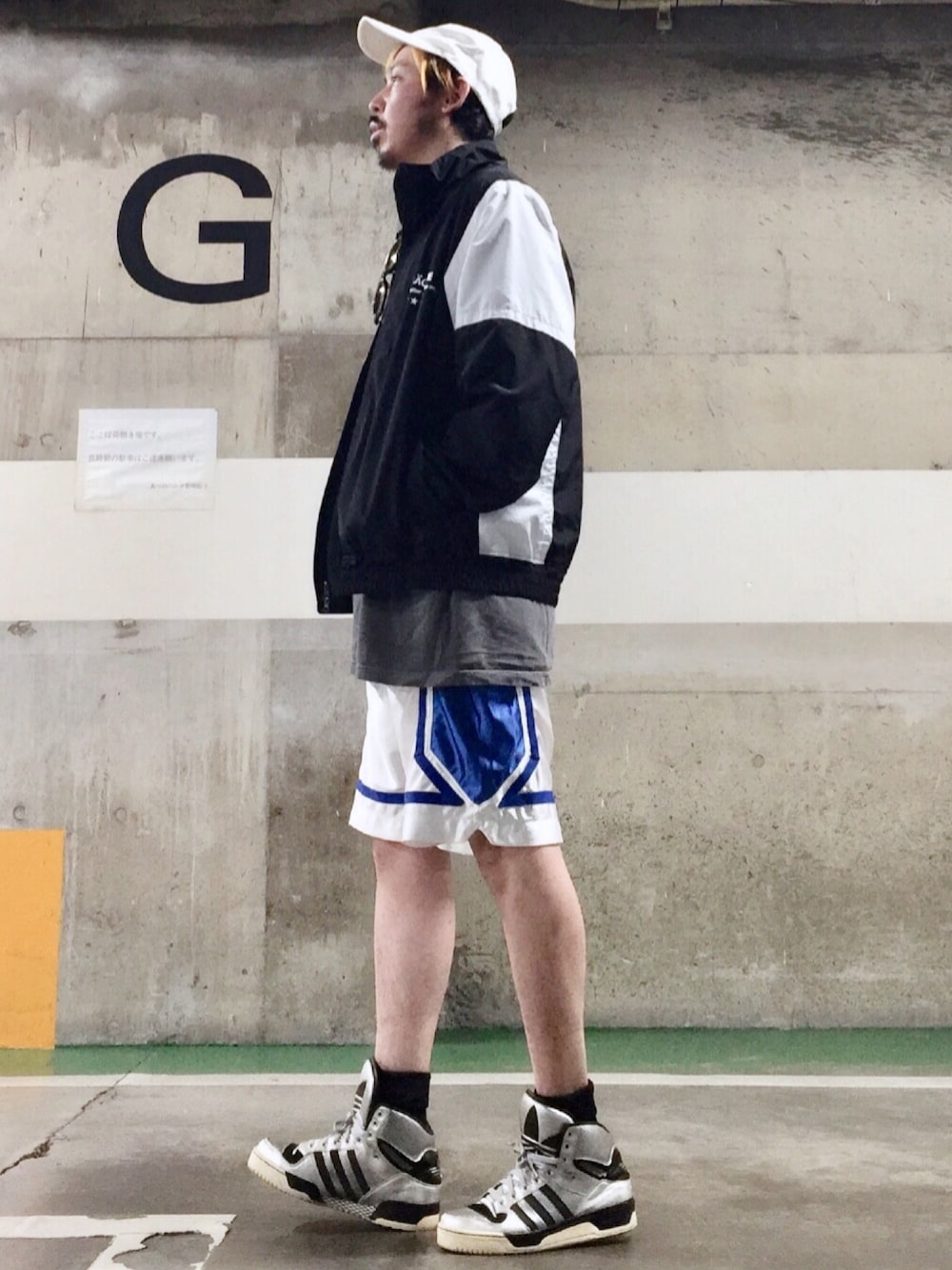 ブラック系のブルゾン、ホワイト系のパンツ、シルバー系のスニーカーを着用したメンズの春コーディネートの1枚目の写真