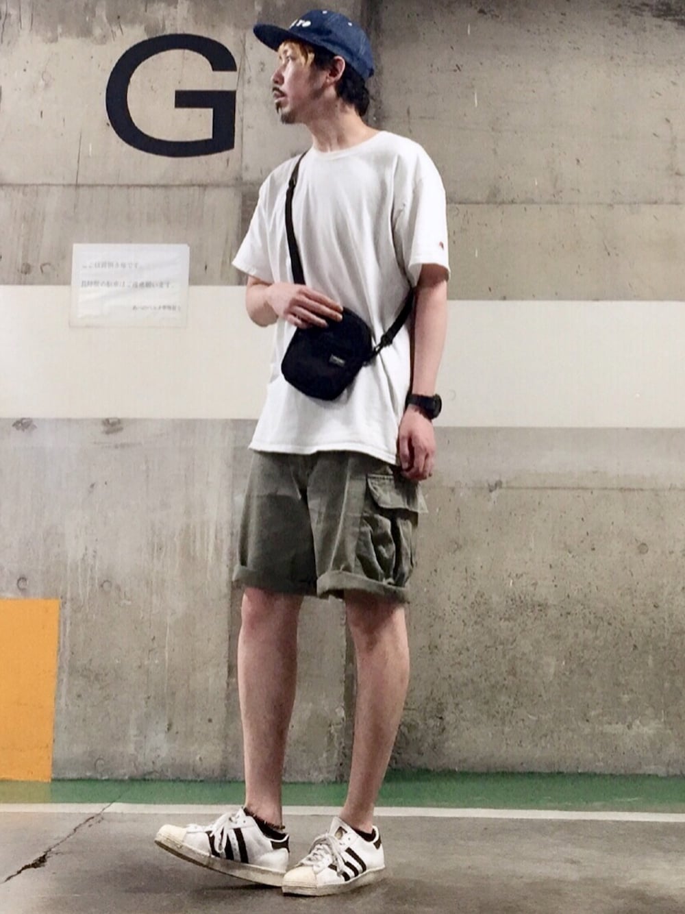 ホワイト系のスニーカー、グリーン系のカーゴパンツ、ブラック系のショルダーバッグを着用したメンズの春コーディネートの1枚目の写真