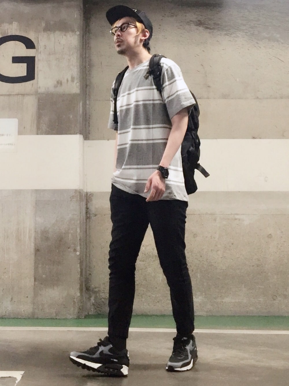 グレー系のTシャツ/カットソー、ブラック系のチノパンツ、ブラック系のスニーカーを着用したメンズの春コーディネートの1枚目の写真