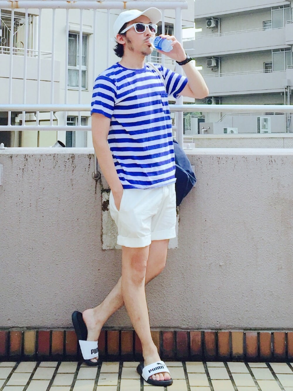 ブルー系のTシャツ/カットソー、ブルー系のバックパック/リュック、ホワイト系のチノパンツを着用したメンズの夏コーディネートの1枚目の写真