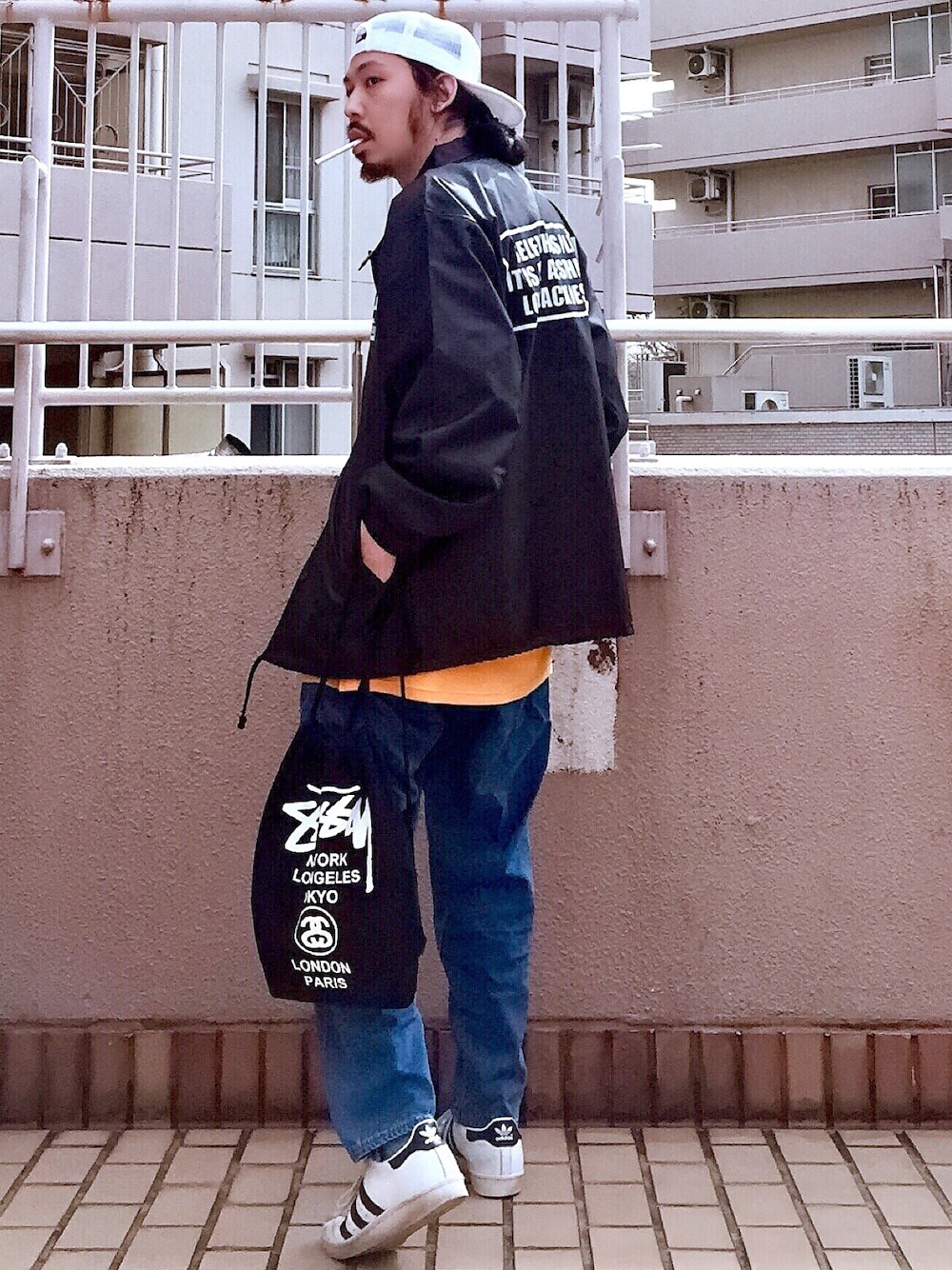 ブラック系のナイロンジャケット、イエロー系のTシャツ/カットソー、ブルー系のデニムパンツを着用したメンズの冬コーディネートの1枚目の写真