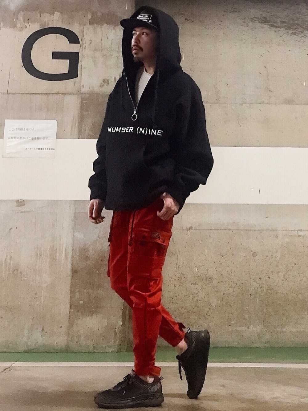 ブラック系のパーカー、ブラック系のスニーカー、レッド系のカーゴパンツを着用したメンズの冬コーディネートの1枚目の写真