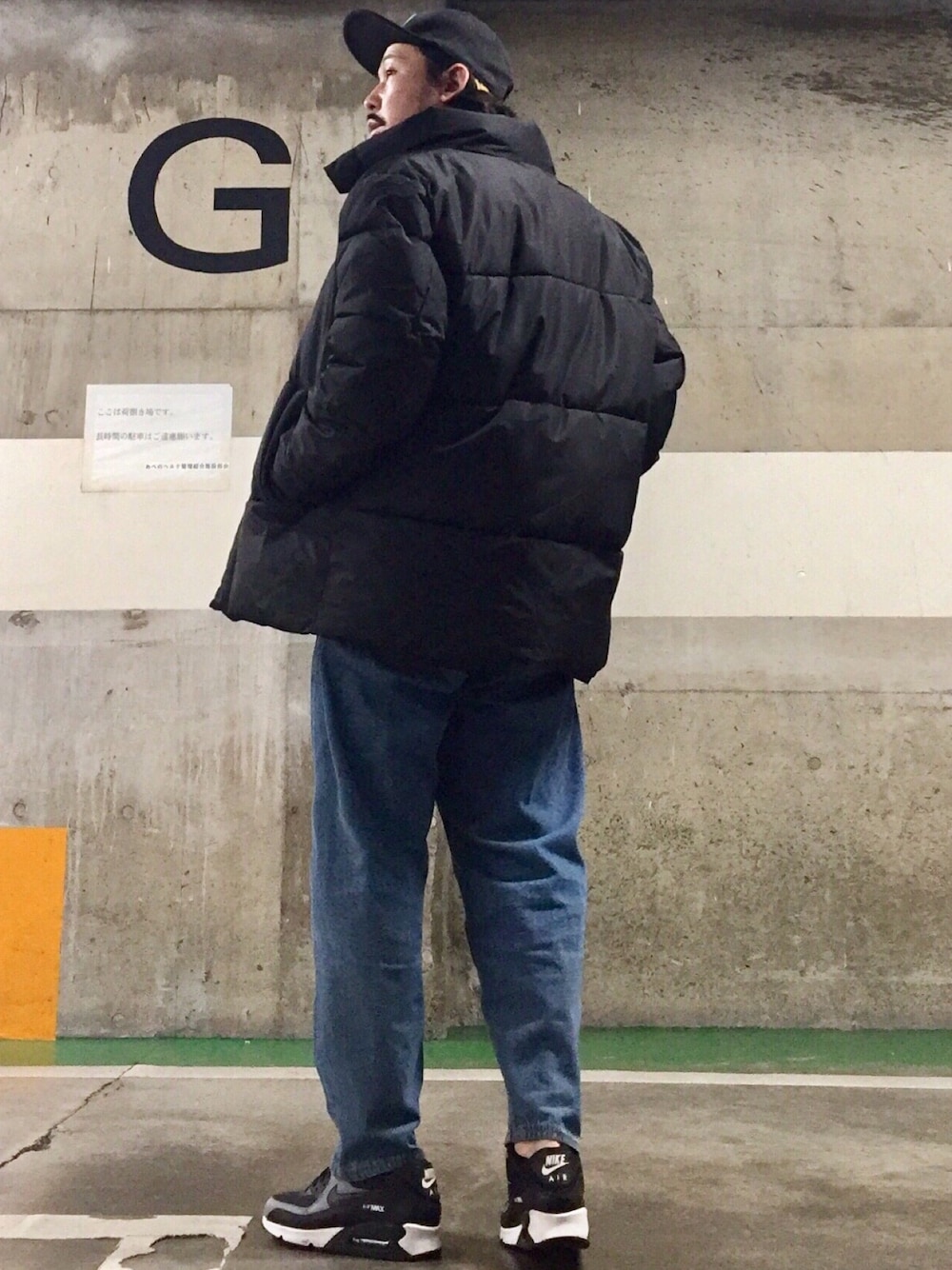 ブラック系のスニーカー、ブラック系のダウンジャケット/コート、ブルー系のデニムパンツを着用したメンズの冬コーディネートの1枚目の写真