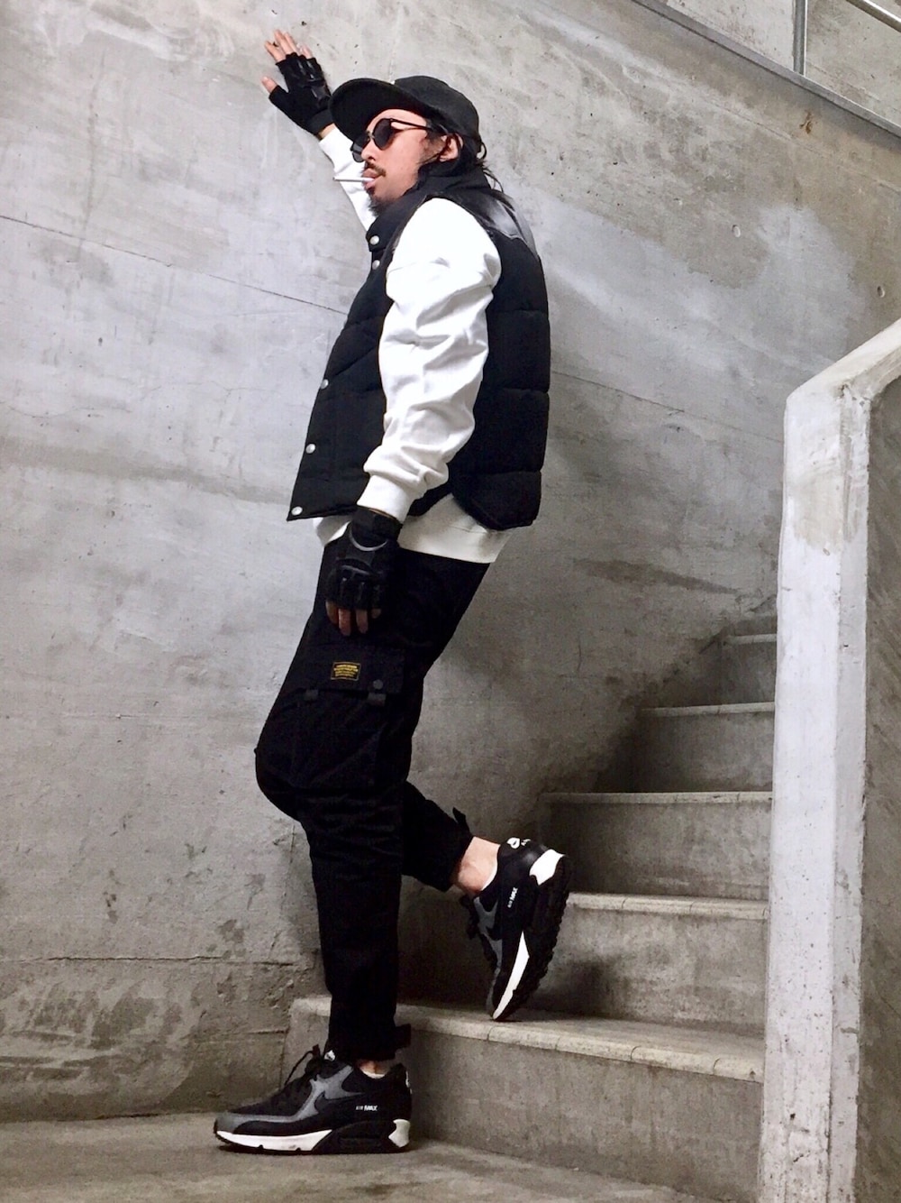 ブラック系のダウンベスト、ブラック系のカーゴパンツ、ブラック系のスニーカーを着用したメンズの冬コーディネートの1枚目の写真