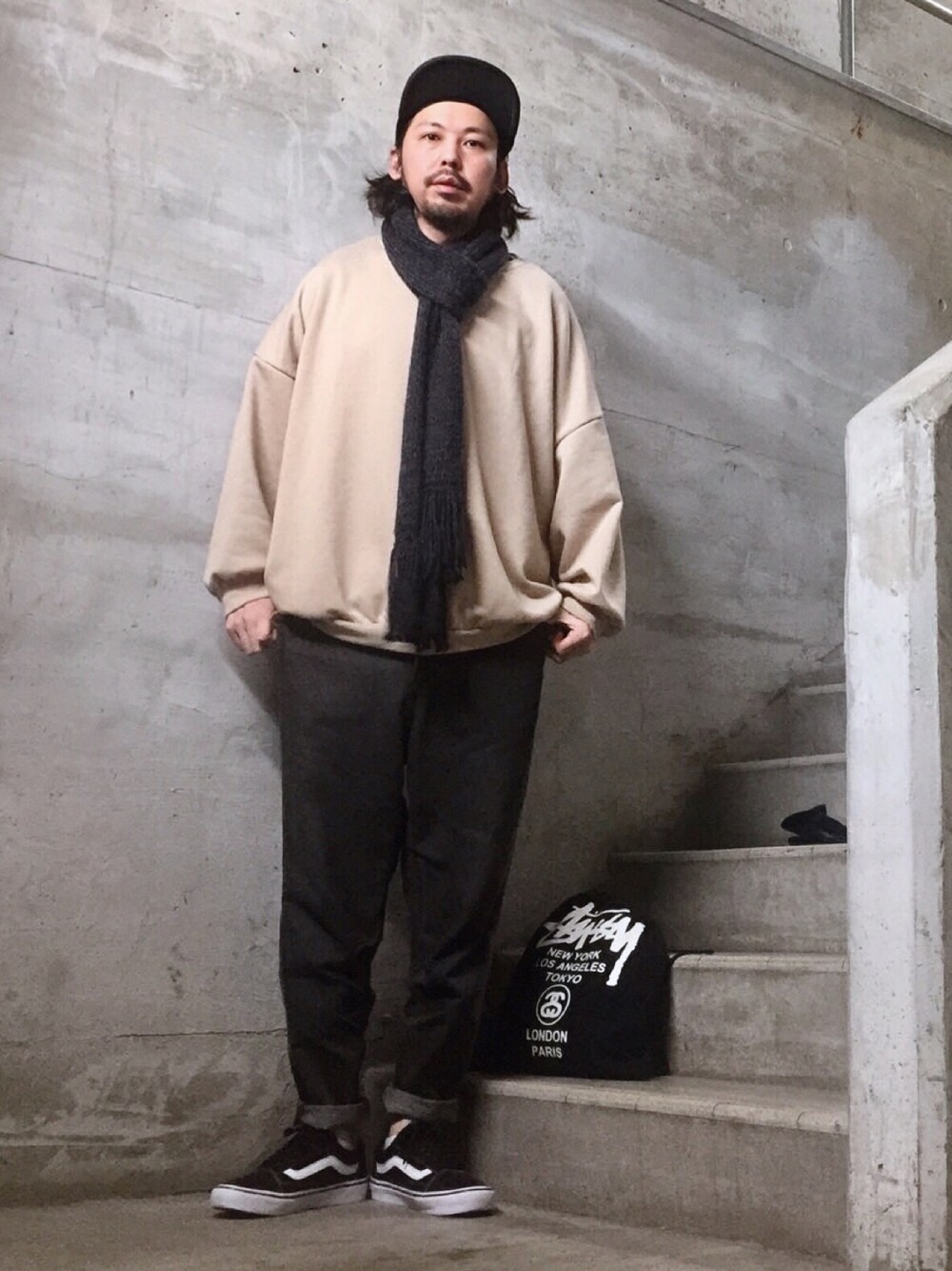 ブラック系のデニムパンツ、ブラック系のスニーカー、ブラック系のバッグを着用したメンズの冬コーディネートの1枚目の写真