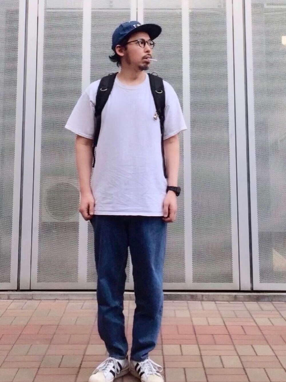 ブルー系のデニムパンツ、ホワイト系のスニーカー、ホワイト系のTシャツ/カットソーを着用したメンズの夏コーディネートの1枚目の写真