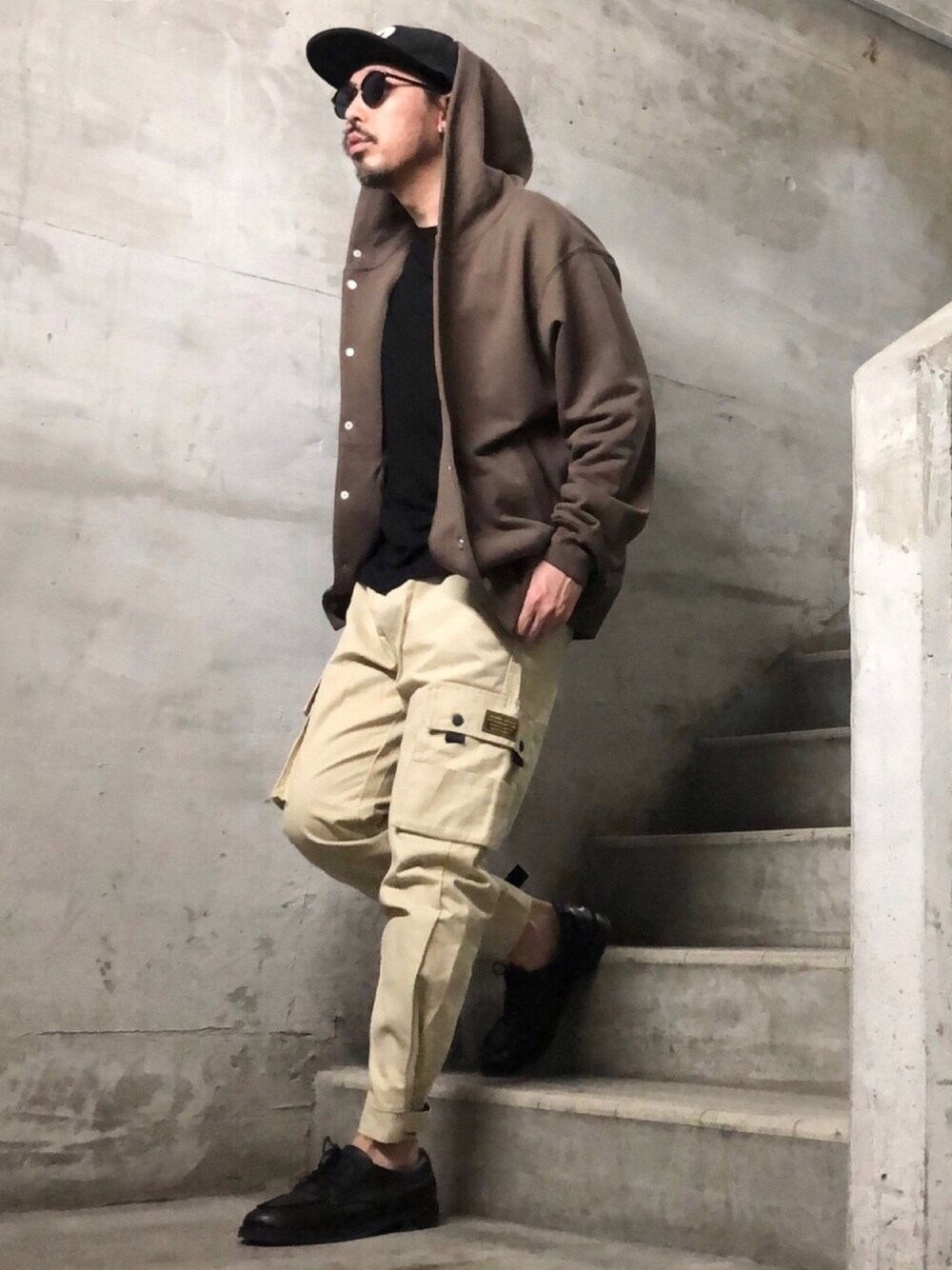 ブラウン系のパーカー、ベージュ系のカーゴパンツ、ブラック系のTシャツ/カットソーを着用したメンズの秋コーディネートの1枚目の写真