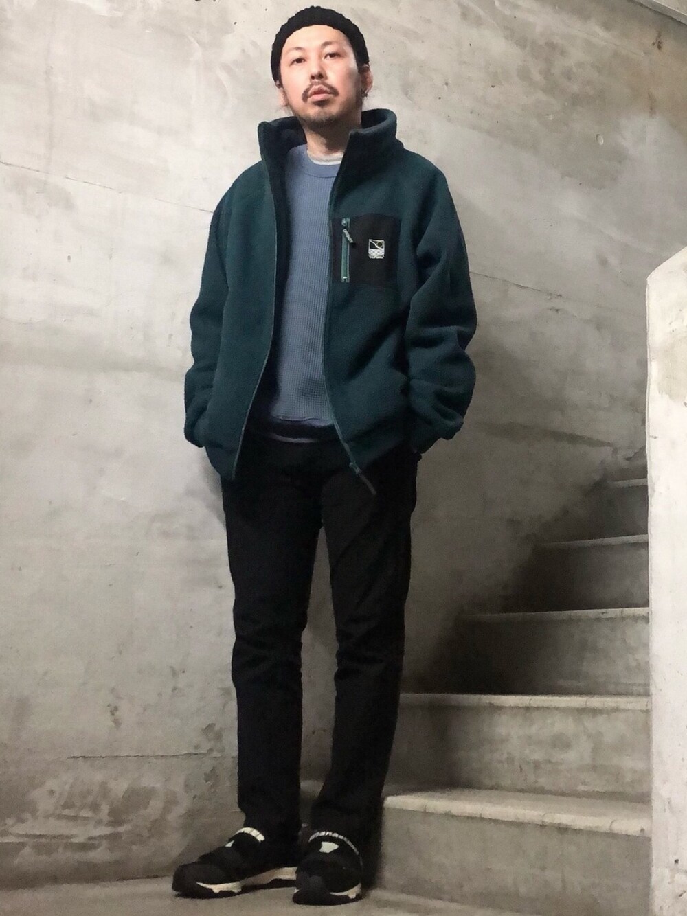 グリーン系のブルゾン、ブルー系のTシャツ/カットソー、ブラック系のスニーカーを着用したメンズの秋コーディネートの1枚目の写真