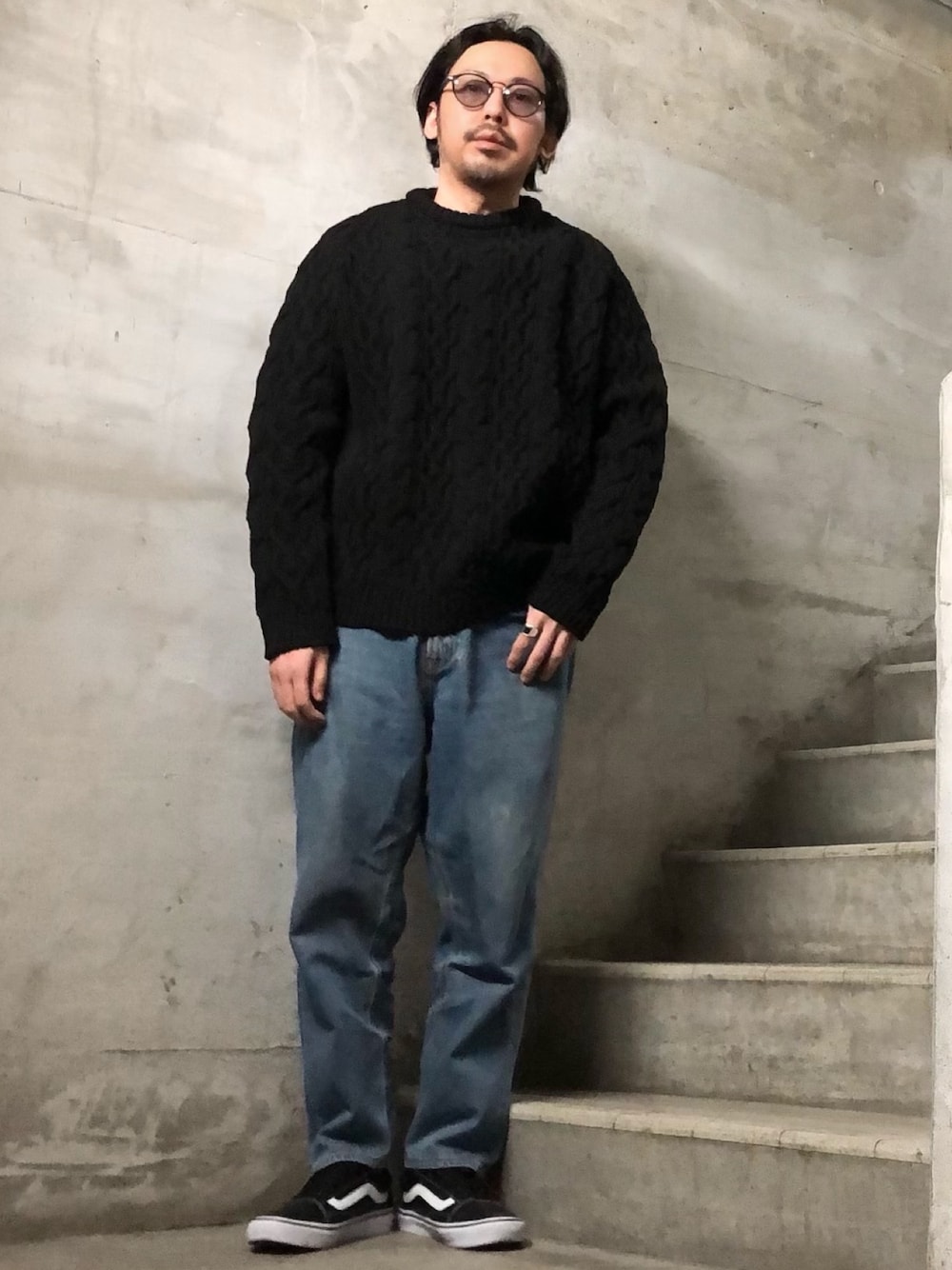 ブラック系のニット/セーター、ブルー系のデニムパンツ、ブラック系のスニーカーを着用したメンズの冬コーディネートの1枚目の写真