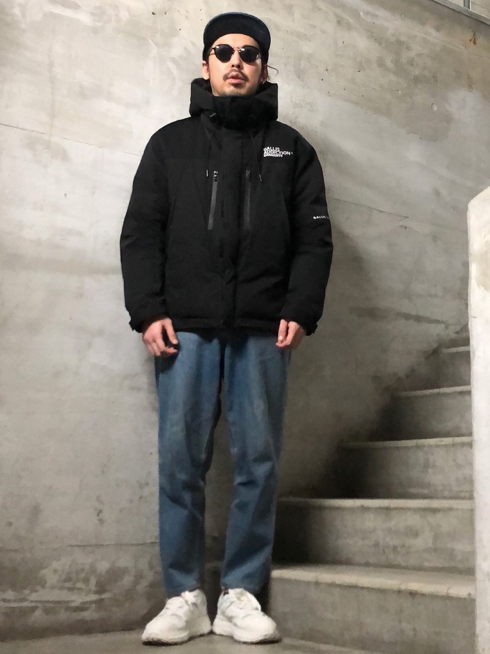 ブラック系のダウンジャケット/コート、ブルー系のデニムパンツ、ブラック系のキャップを着用したメンズの冬コーディネートの1枚目の写真