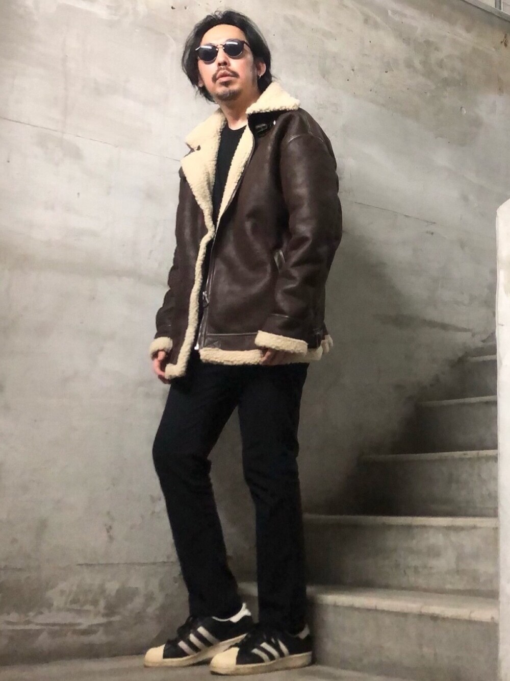 ブラウン系のムートンコート、ブラック系のTシャツ/カットソー、ブラック系のチノパンツを着用したメンズの冬コーディネートの1枚目の写真