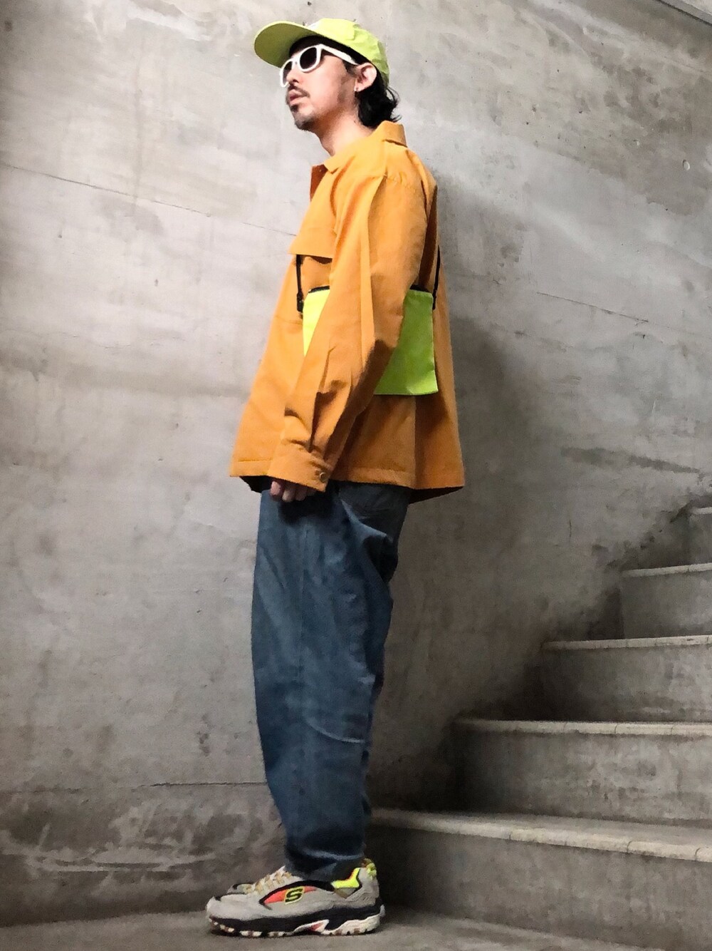 イエロー系のミリタリージャケット、ブルー系のデニムパンツ、グレー系のスニーカーを着用したメンズの春コーディネートの1枚目の写真