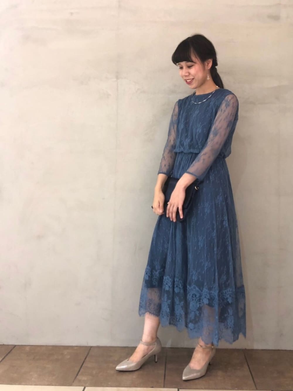 ブルー系のドレス、ブルー系のクラッチバッグ、シルバー系のパンプスを着用したレディースの秋コーディネートの1枚目の写真