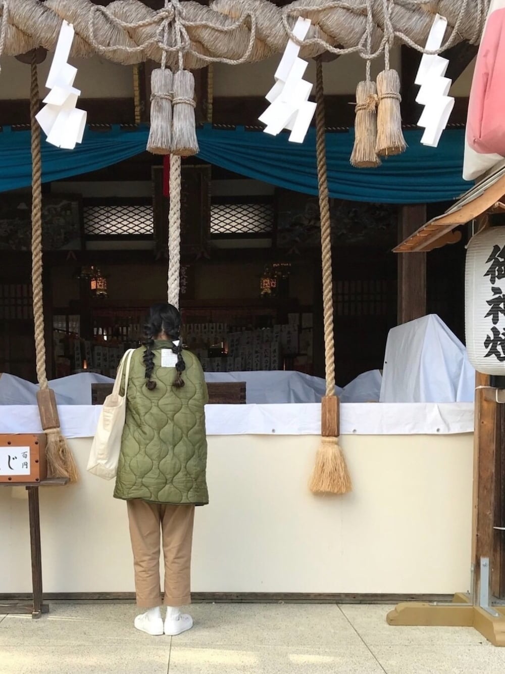 グリーン系のミリタリージャケット、ベージュ系のチノパンツ、ホワイト系のスニーカーを着用したレディースの冬コーディネートの1枚目の写真