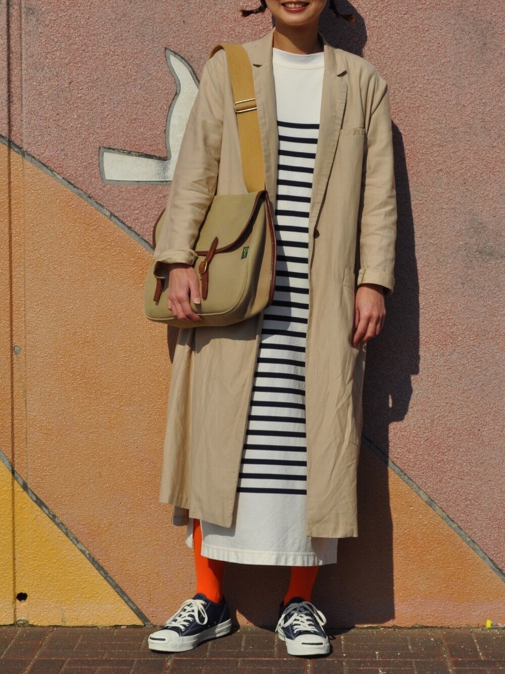 ブルー系のワンピース、ベージュ系のジャケット/アウター、ブルー系のスニーカーを着用したレディースの春コーディネートの1枚目の写真