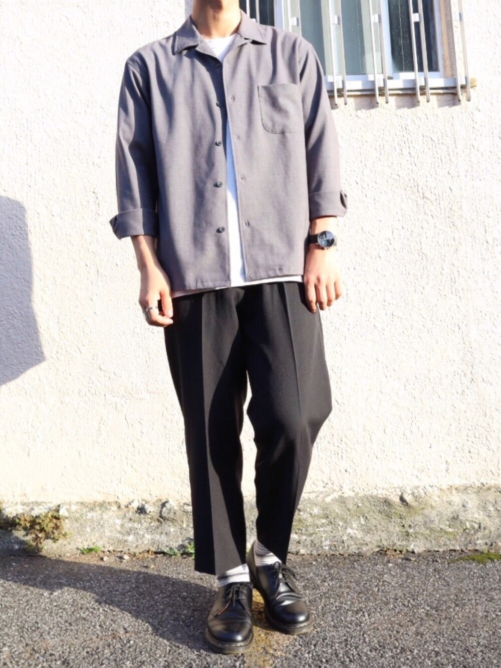 ブラック系のドレスシューズ、グレー系のスラックス、ホワイト系のTシャツ/カットソーを着用したメンズの春コーディネートの1枚目の写真