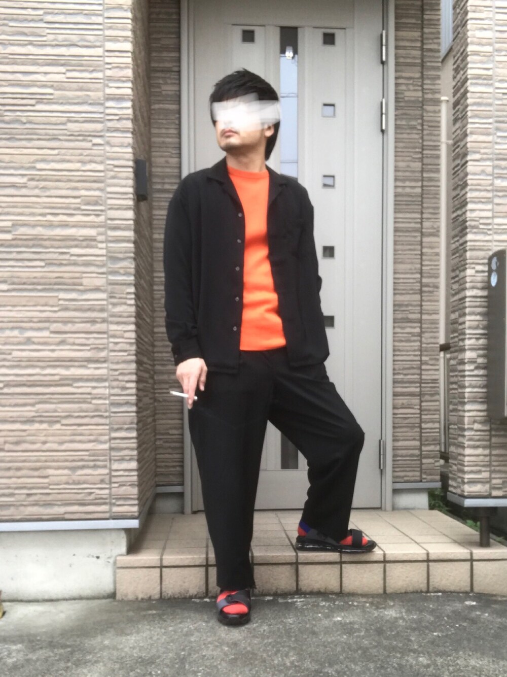 グレー系のサンダル、ブラック系のその他パンツ、オレンジ系のTシャツ/カットソーを着用したメンズの春コーディネートの1枚目の写真