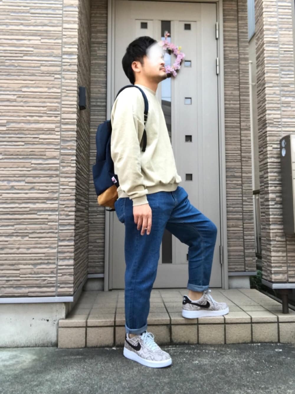 ホワイト系のスニーカー、ブルー系のデニムパンツ、ベージュ系のスウェットを着用したメンズの春コーディネートの1枚目の写真